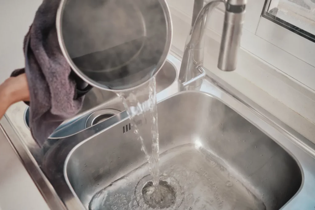 steaming water being poured down a kitchen drain