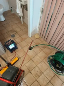 CCTV drain camera monitor beside a hydro-jetting hose reel at an open floor drain