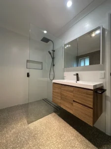 Walk-in shower with a floating timber vanity in a renovated bathroom.